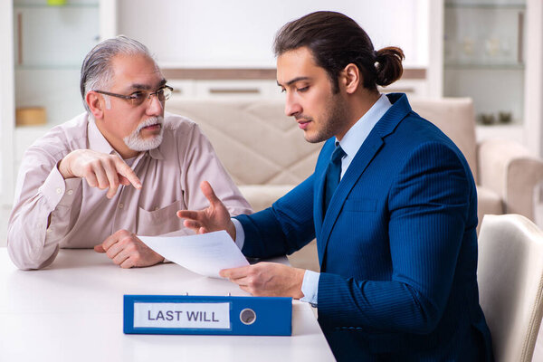 An older man seated at a table with a younger man in a suit.