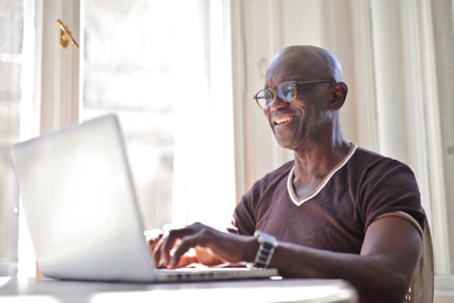A man seated at a desk working on a laptop.